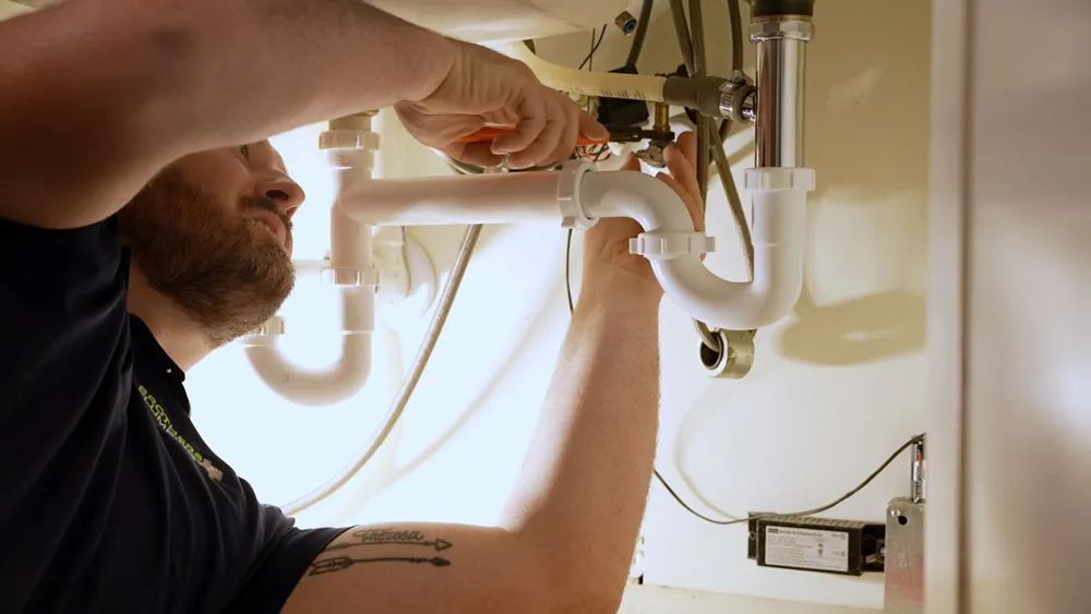 Plumber repairing a pipe under a sink in San Angelo & Abilene, TX