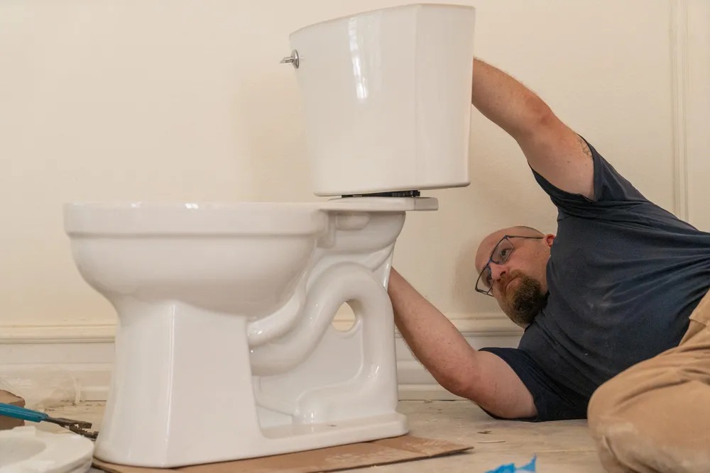 Plumber installing a toilet tank in San Angelo & Abilene, TX